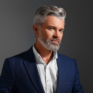 Portrait of confident man with beautiful hairstyle on dark background